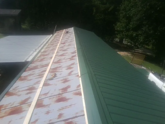 Old rusted panels beside newly installed green metal roofing — Wind Damage Roof Repair by Roofing Brothers in Niantic