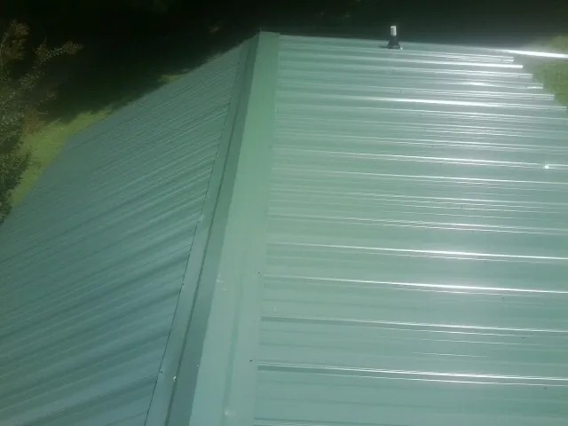 New green metal panels meeting at the ridge of a roof — Flat Roof Repair work by our crew in Niantic