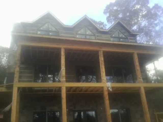 Dormers and porch framing on a large log home under construction — Roof Coating work by our crew in Niantic