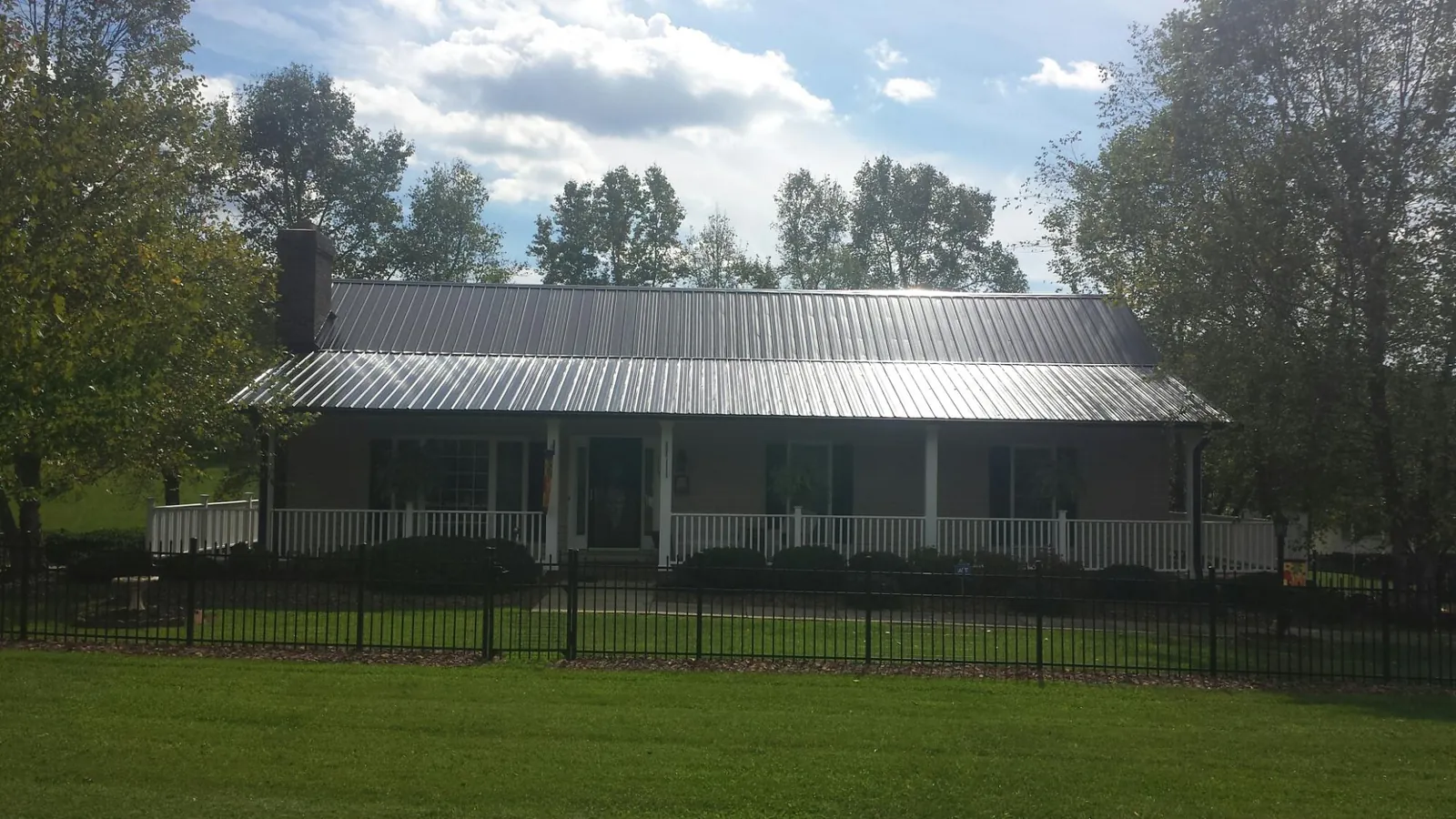 Gray metal roof on a brick ranch with a full width front porch — Gutter Guard Installation work by our crew in Niantic